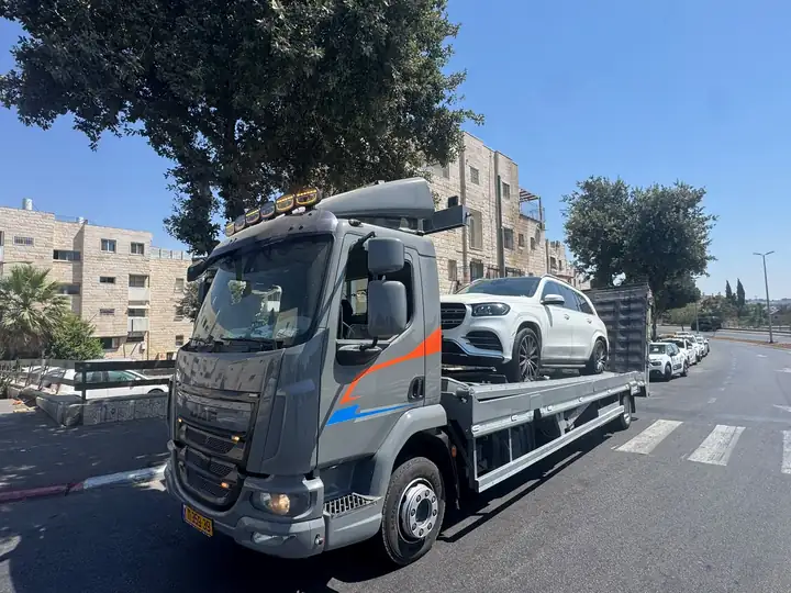 רכב יוקרה לבן על הגרר של שילת ברחוב עירוני